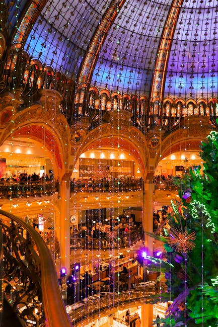 Illuminated view of a decorated Paris shopping mall interior during the holiday season.